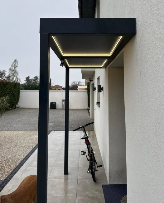 Freestanding aluminium canopy on posts along a side passage with LED lighting