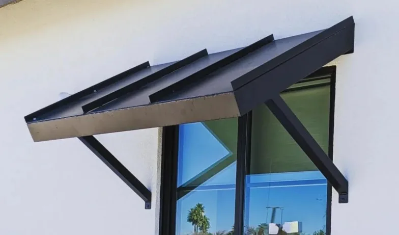 Sloped standing seam aluminium awning on angled support arms over a window